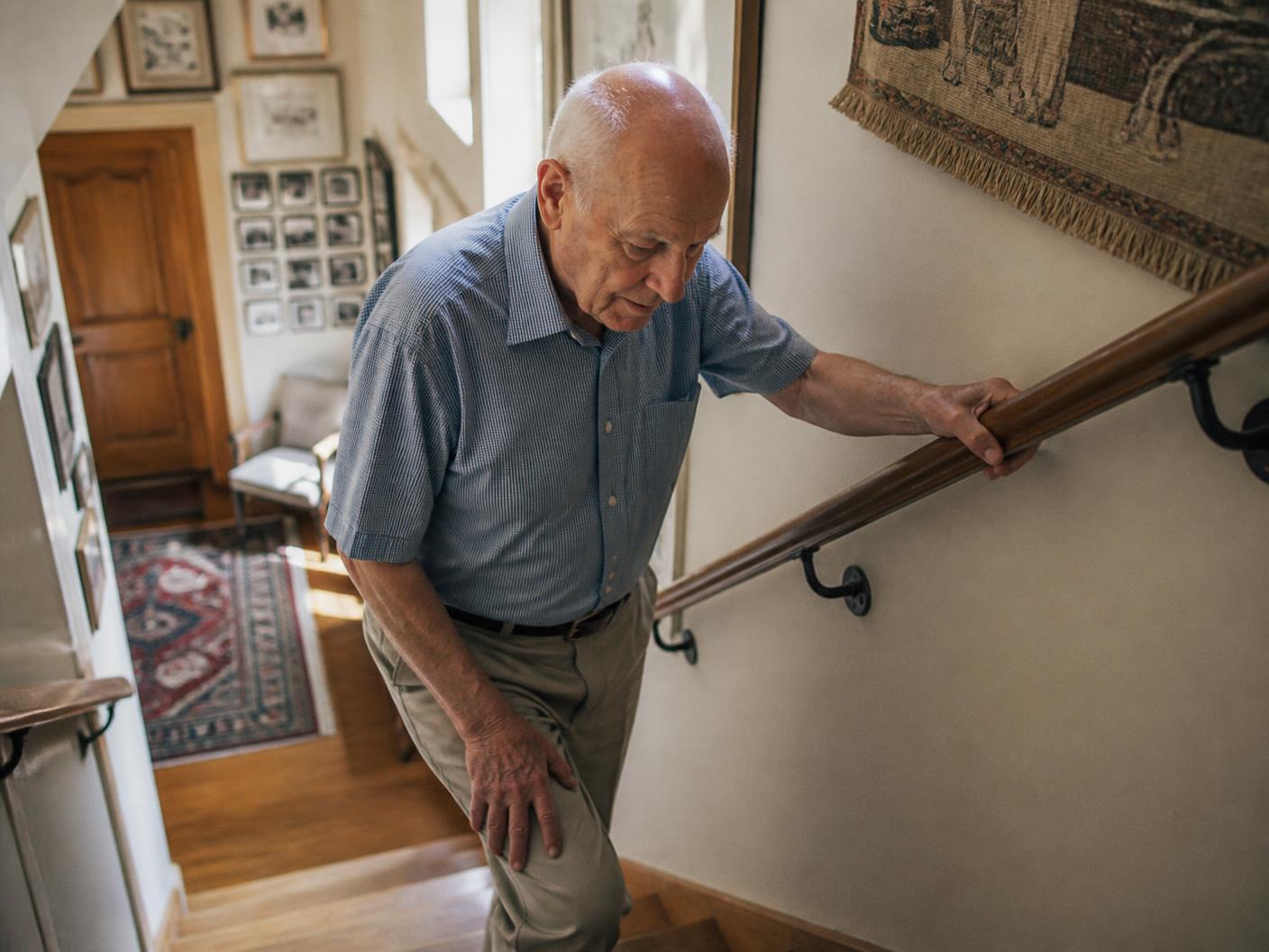An older man steadying himself on a handrail at home